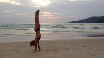 Julia steht am Sandstrand im Handstand (Thailand)
